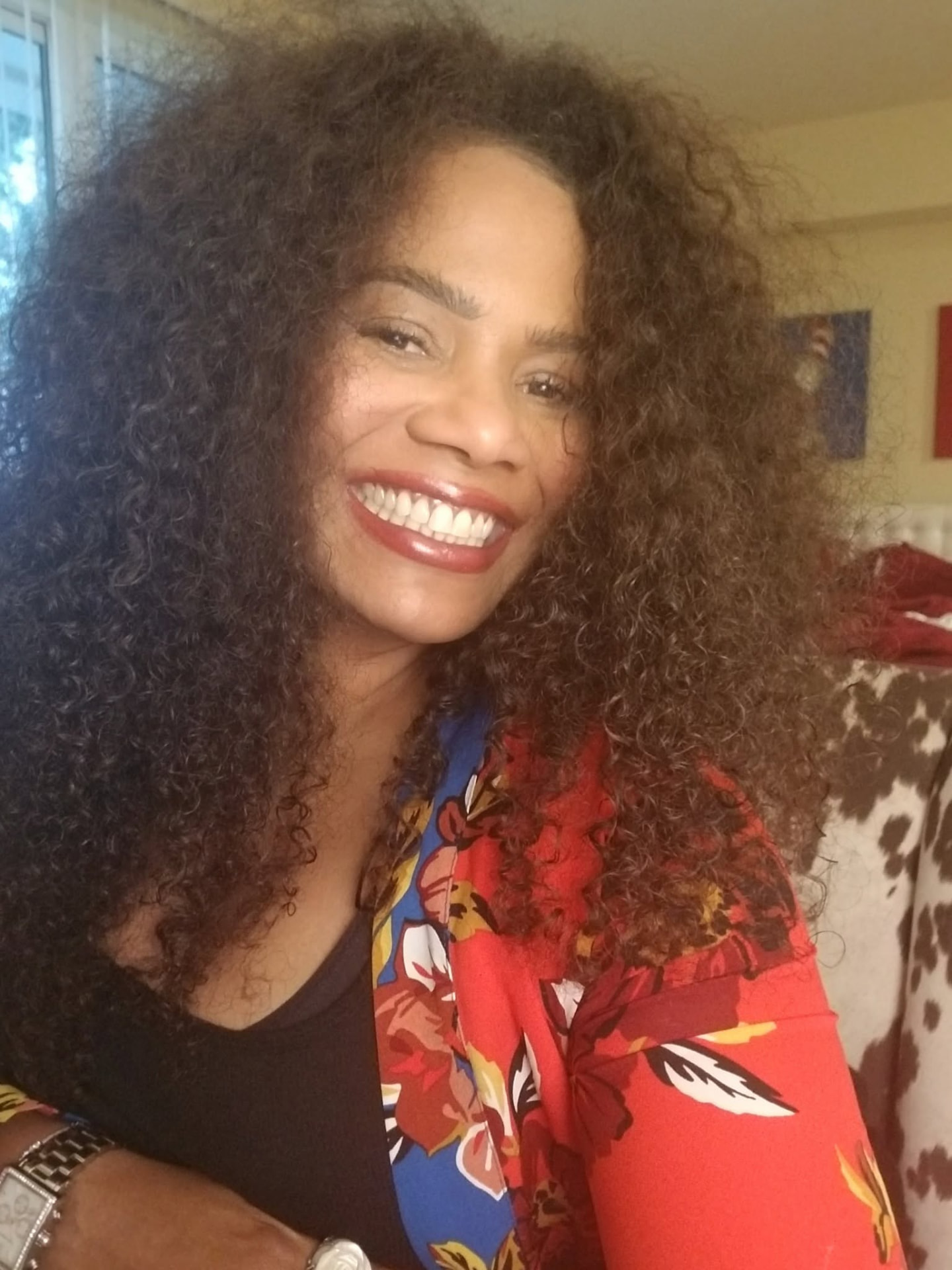 Chilone smiling brightly at home in a red and blue floral wrap