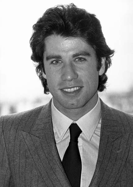 Black-and-white press portrait of a man in a pinstripe suit and tie